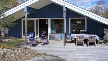 A building with a covered porch, outdoor seating, and a view of the surrounding landscape.