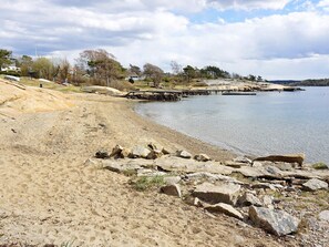 A sandy beach with rocks, a calm lake, and a wooden pier extending into the water. - 6 Person Holiday Home in Stromstad (Stromstad)