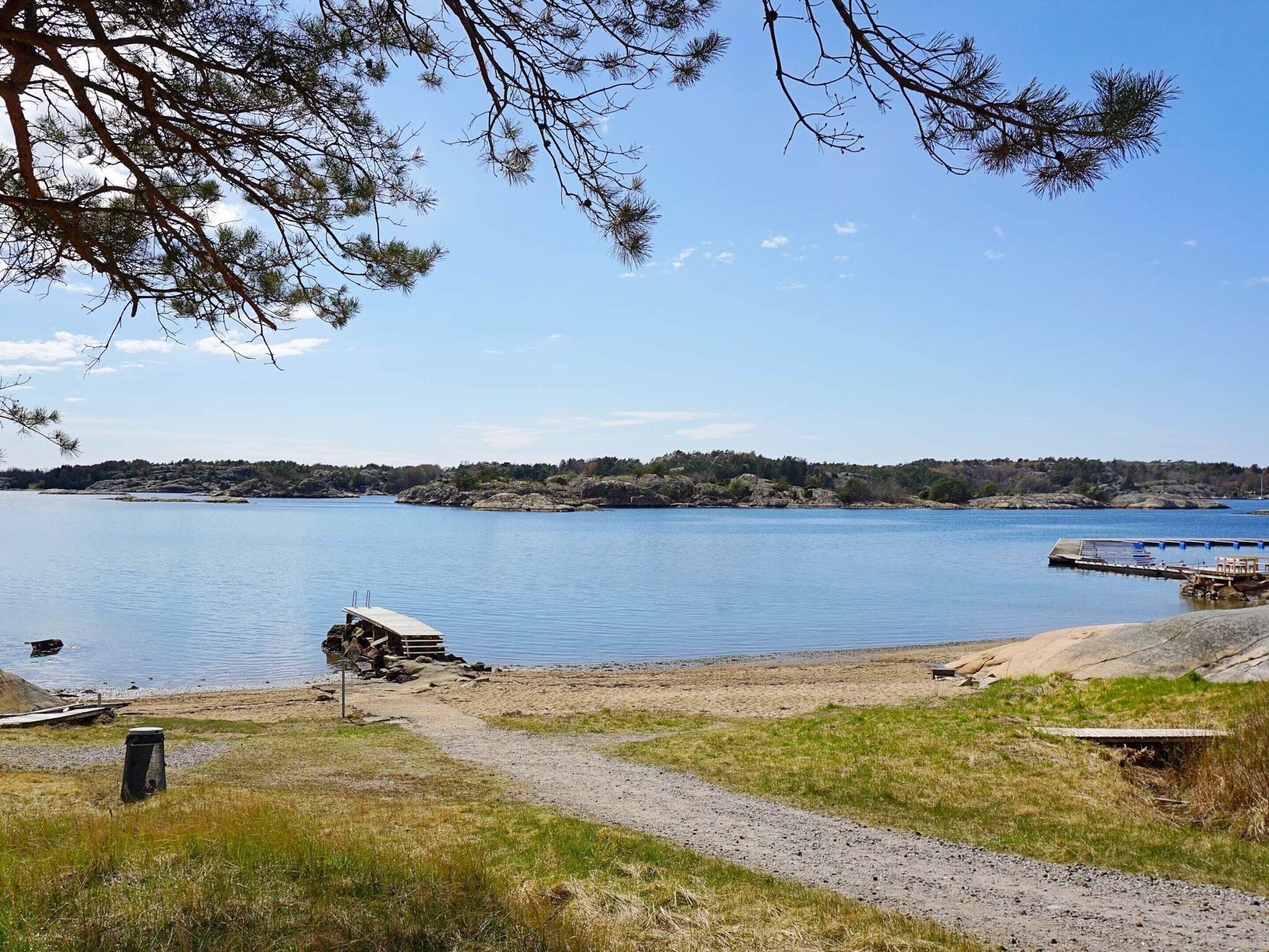A lakeside view with a dock, a boat, and a path leading to the water.