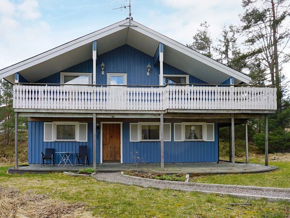 A two-story blue house with a balcony, a wooden door, and a small patio area. - 6 Person Holiday Home in Stromstad (Stromstad)