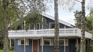 A two-story building with a balcony, surrounded by trees and a well-maintained lawn.