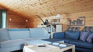 L’intérieur d’un chalet en bois chaleureux et accueillant, avec un canapé, une table basse et une bibliothèque.