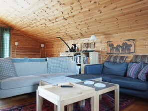 L’intérieur d’un chalet en bois chaleureux et accueillant, avec un canapé, une table basse et une bibliothèque.