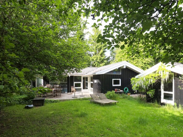 A house with a covered patio, a small deck, and a garden area.