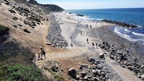 Una playa con terreno rocoso y una vista despejada del océano.