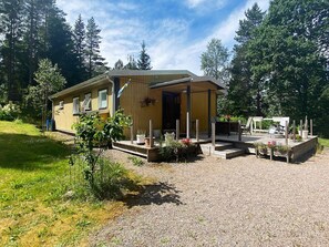 A wooden cabin with a porch, surrounded by a gravel driveway and a garden. - 6 Person Holiday Home in Bottnaryd (Bottnaryd)