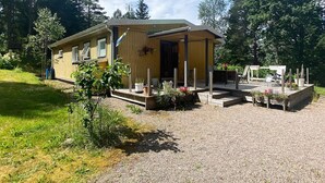 A wooden cabin with a porch, surrounded by a gravel driveway and a grassy area. - 6 Person Holiday Home in Bottnaryd (Bottnaryd)