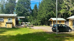 A cabin with a porch, a car parked nearby, and a forested backdrop. - 6 Person Holiday Home in Bottnaryd (Bottnaryd)