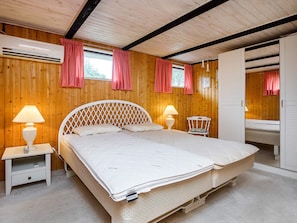 A bedroom with a large bed, two bedside tables with lamps, a chair, and a wardrobe.