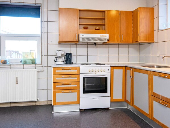 A compact kitchen with wooden cabinets, a white stove, and a coffee maker on the countertop.