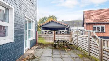 A courtyard with a wooden fence, a bench, and a small covered area.