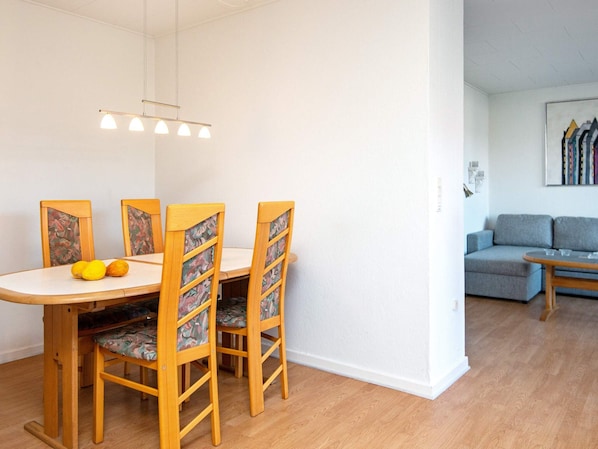 A dining area with a wooden table and chairs, a hanging light fixture, and a grey sofa in the background. - 4 Person Holiday Home in Ansager (Ansager)