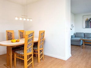 A dining area with a wooden table and chairs, a hanging light fixture, and a grey sofa in the background. - 4 Person Holiday Home in Ansager (Ansager)