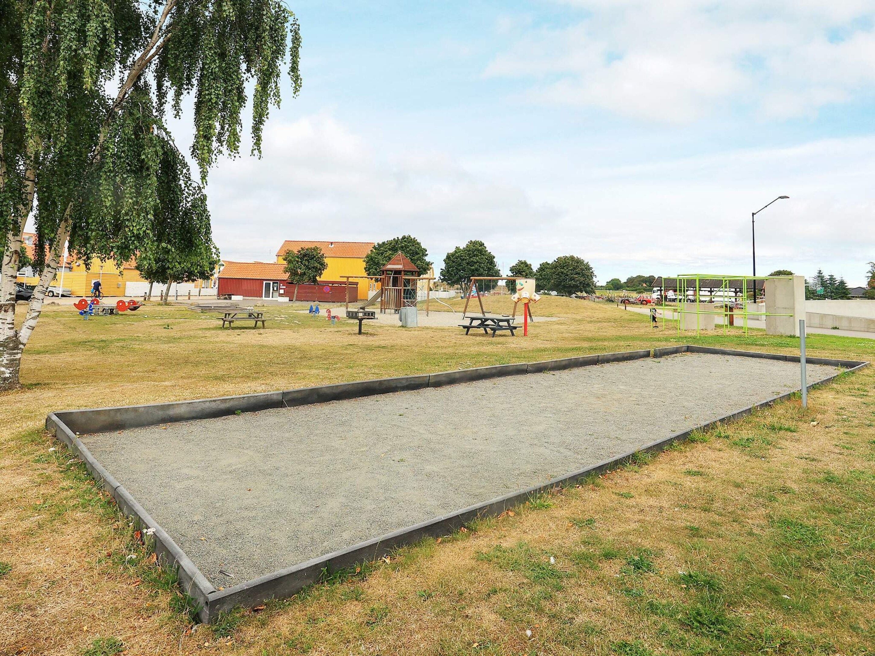 Ein Park mit einer großen offenen Fläche, Spielgeräten und einem Gebäude im Hintergrund.