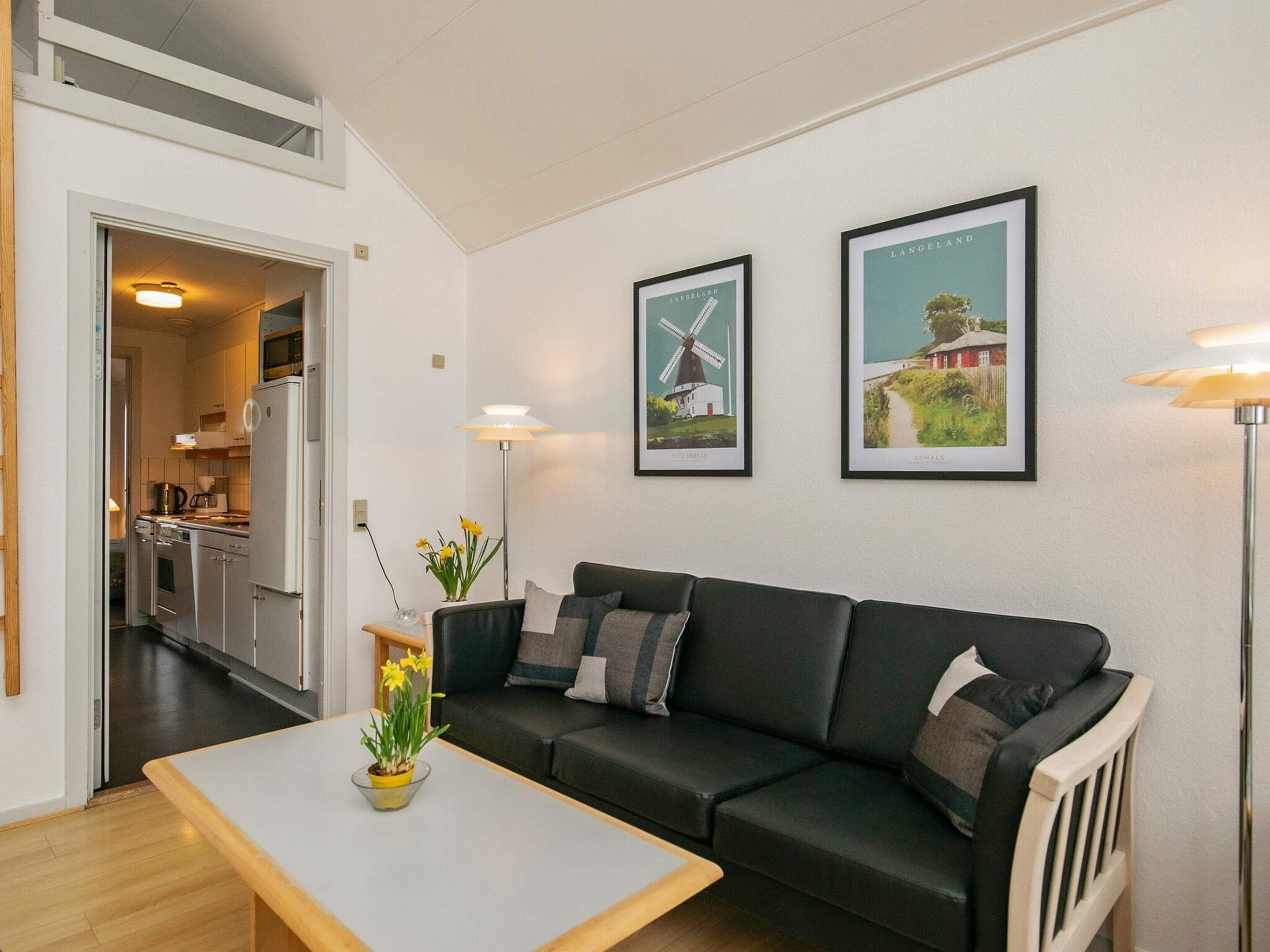 A modern living room with a sofa, coffee table, and two framed pictures on the wall.