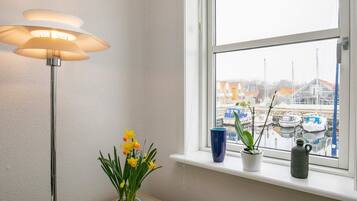A room with a window, a floor lamp, and a potted plant with yellow flowers.