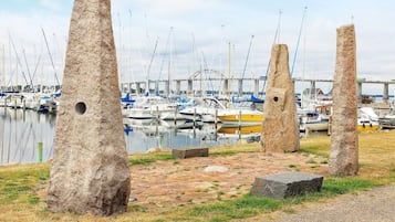 A marina with boats docked, stone pillars, and a bridge in the background.