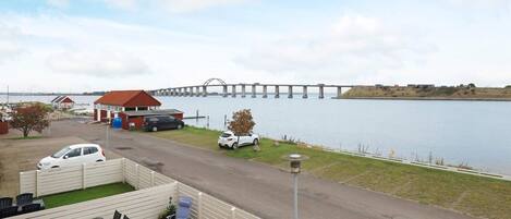 A waterfront property with a dining area, a covered outdoor seating, and a view of a bridge.