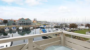 A marina with boats docked, a building with a green roof, and a clear sky.