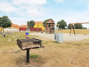A playground with a swing set, a climbing structure, and a slide. - 6 Person Holiday Home in Rudkobing (Rudkobing)