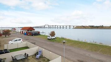 A waterfront property with a dining area, a covered outdoor seating area, and a view of a bridge over water.