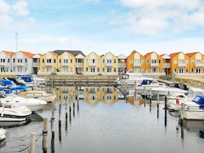 A marina with boats docked, a stone wall, and colorful row houses in the background. - 6 Person Holiday Home in Rudkobing (Rudkobing)