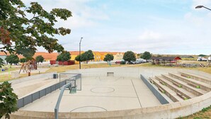 Un campo da basket con una recinzione, una panchina e un’area giochi.