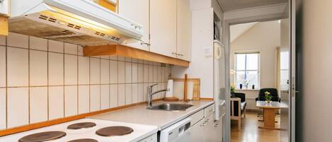 A modern kitchen with white cabinetry, a gas stove, a built-in oven, and a stainless steel sink.