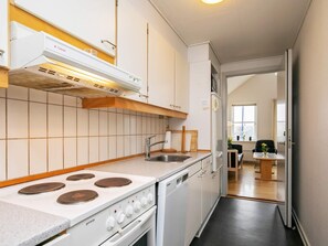 A modern kitchen with white cabinetry, a gas stove, a built-in oven, and a stainless steel sink.
