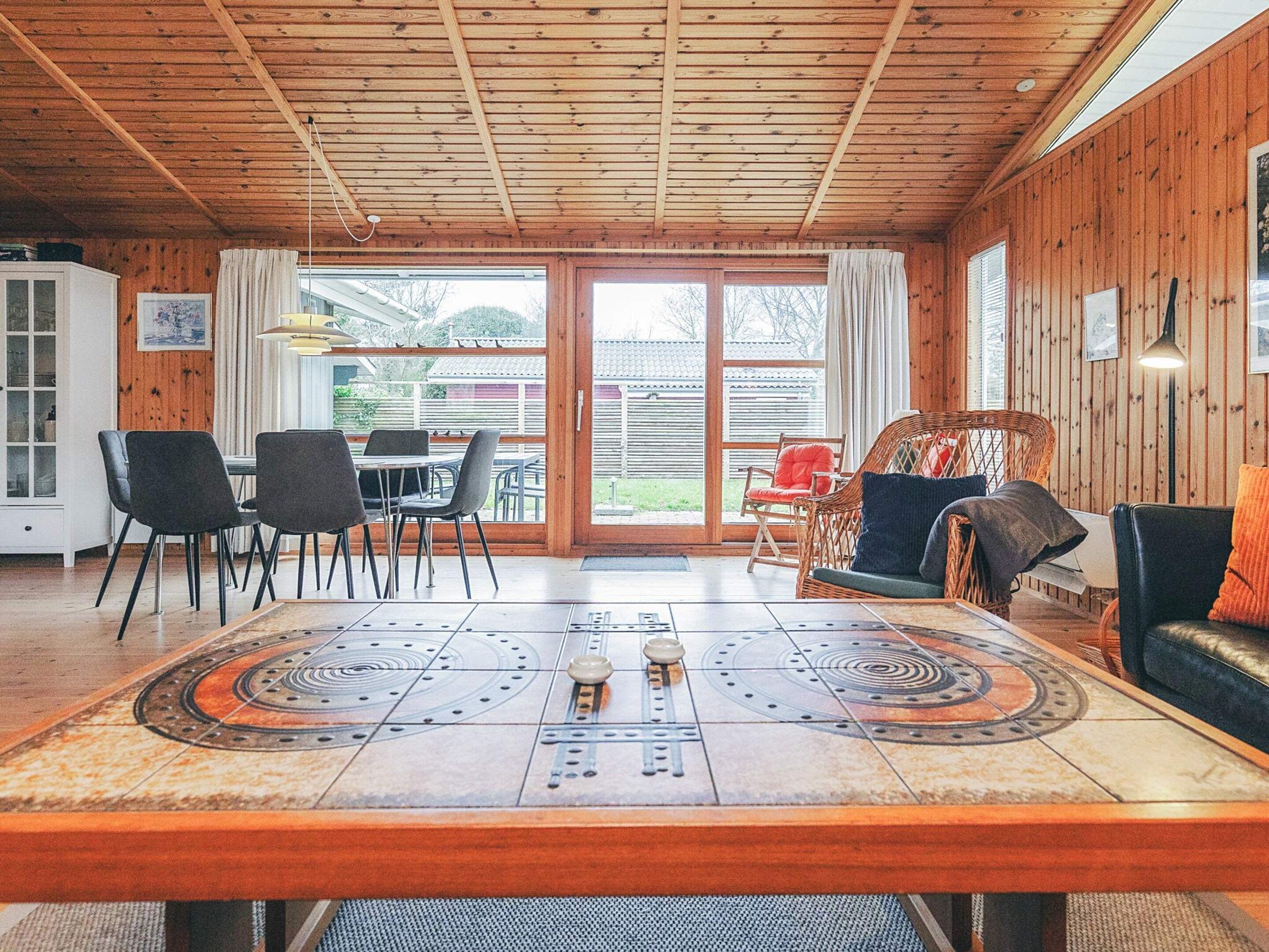 A wooden interior with a dining table, chairs, and a sofa.