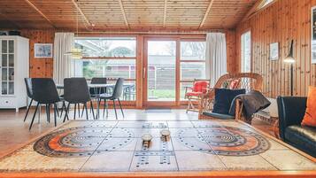 A wooden interior with a dining table, chairs, and a sofa.
