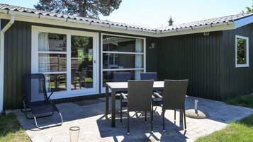 Un patio con mesa y sillas, una zona de estar techada y vistas del paisaje circundante.