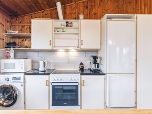A compact kitchen with a microwave, kettle, coffee maker, oven, and a washing machine. - 4 Person Holiday Home in Store Fuglede (Store Fuglede)