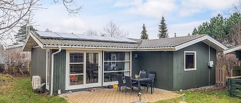 Una casa de un piso con patio, puerta corredera de vidrio y una pequeña terraza.