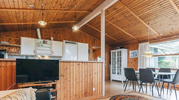 A wooden interior with a TV, sofa, dining table, and cabinets. - 4 Person Holiday Home in Store Fuglede (Store Fuglede)