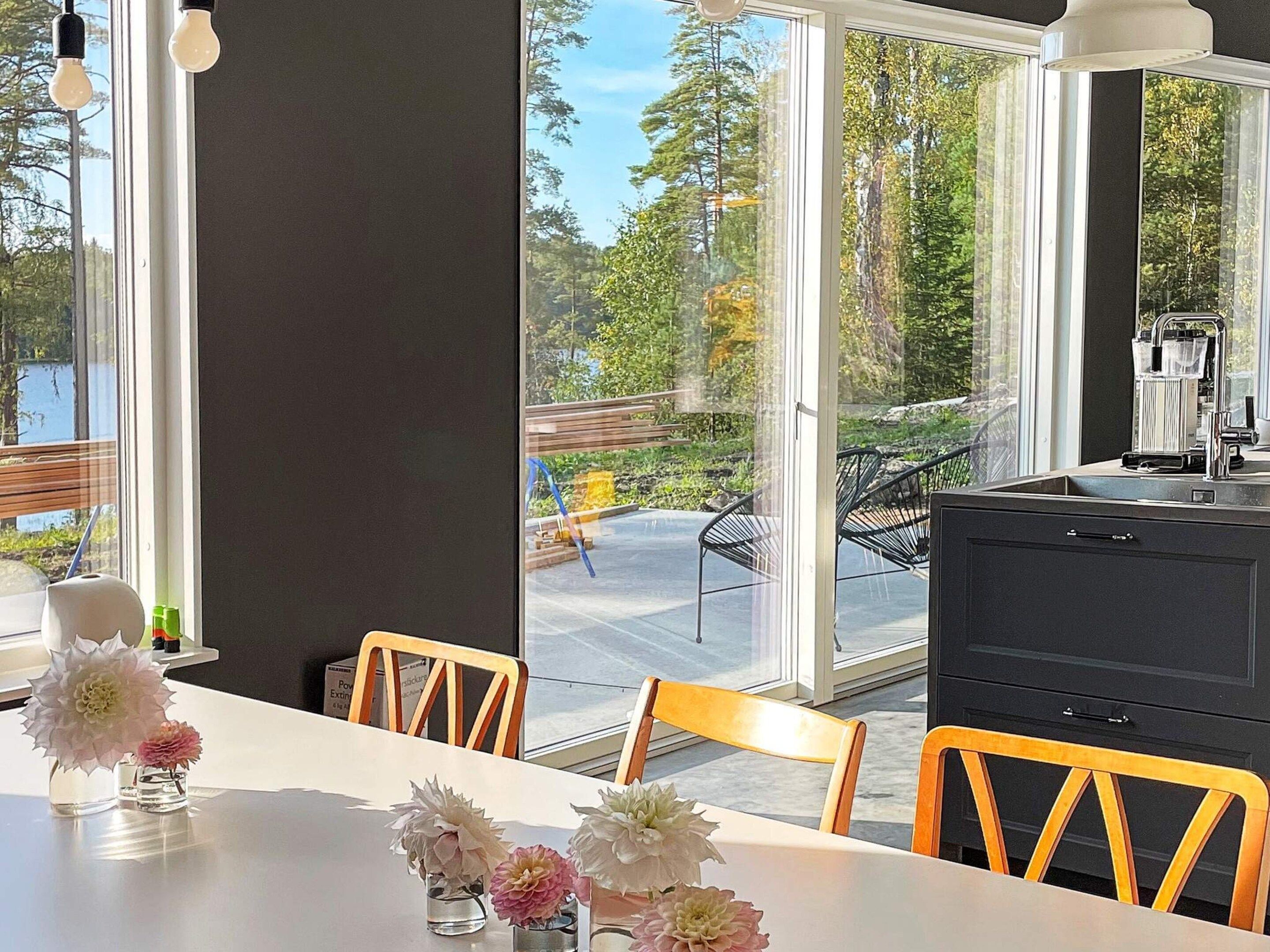 Una cocina moderna con un ventanal grande, una mesa de comedor con sillas y vistas a una terraza y zona exterior.