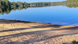 Ein ruhiger See mit bewaldeter Uferlinie und blauem Himmel.