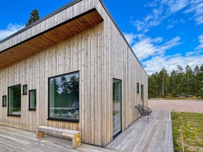 A modern wooden building with large windows, a deck, and a bench. - 5 Star Holiday Home in Hacksvik (Håcksvik)