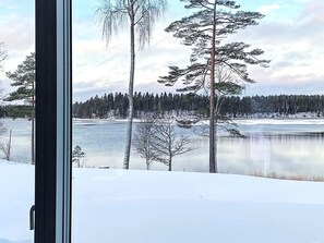 A snowy landscape with a lake, trees, and a clear sky. - 5 Star Holiday Home in Hacksvik (Håcksvik)