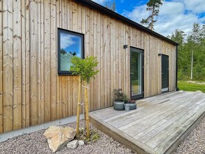 A modern wooden building with a deck, large windows, and a door. - 5 Star Holiday Home in Hacksvik (Håcksvik)