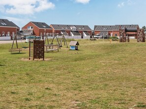 A residential area with houses, a playground, and a small blue structure. - 4 Person Holiday Home in Romo (Rømø)