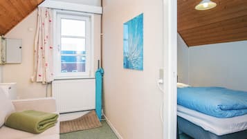 Un dormitorio pequeño y acogedor con una cama individual, una ventana con cortinas, un radiador y un cuadro en la pared.