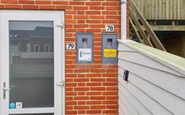 Un bâtiment en briques avec une porte blanche et deux boîtes aux lettres portant les numéros 78 et 79.