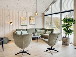 A modern living room with a sectional sofa, two armchairs, a coffee table, and a large window with a view of the outdoors. - 5 Star Holiday Home in Jaegerspris (Jægerspris)