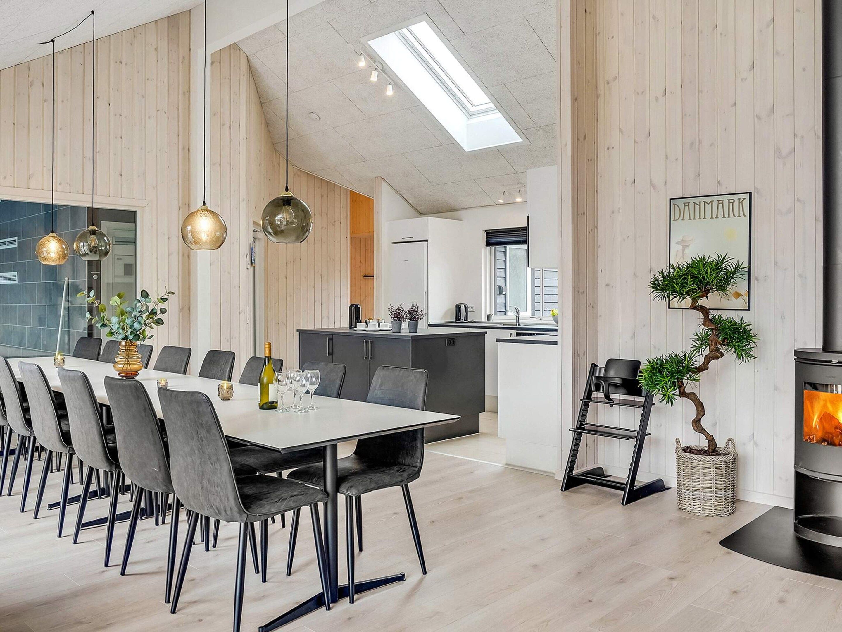 Een moderne eetruimte met een lange tafel, stoelen en hanglampen.