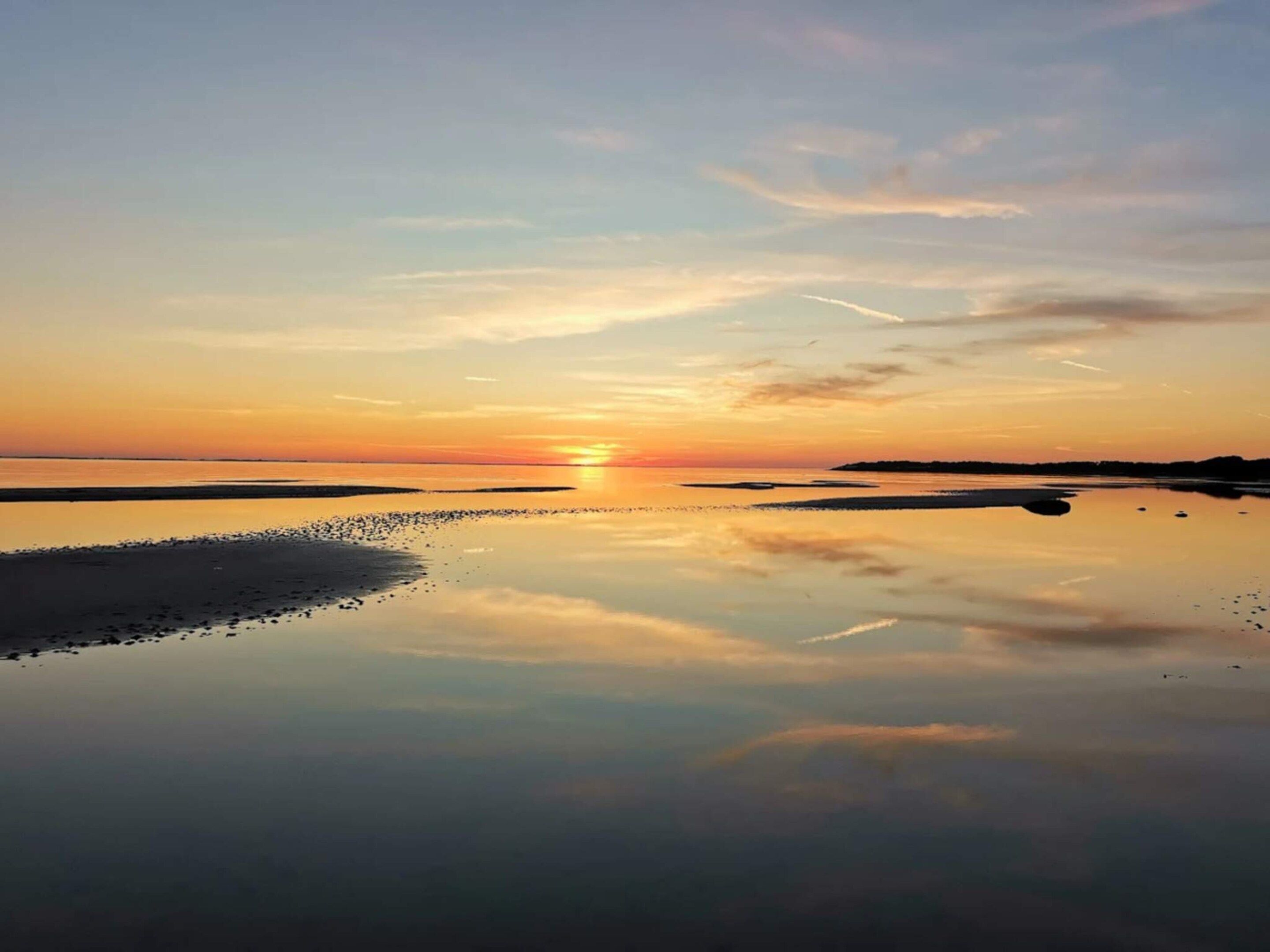 A calm body of water reflecting the sky during sunset.