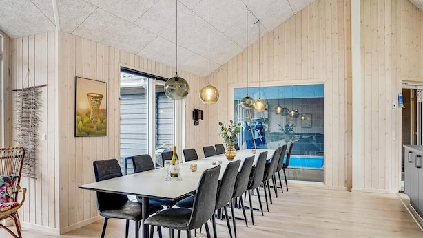 A modern dining area with a long table, chairs, and pendant lighting. - 5 Star Holiday Home in Jaegerspris (Jægerspris)