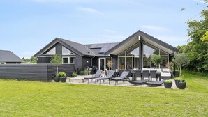 A modern house with a patio area featuring outdoor furniture and a swimming pool. - 5 Star Holiday Home in Jaegerspris (Jægerspris)