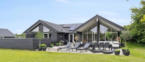Une maison moderne dotée d’un patio aménagé avec du mobilier d’extérieur et une piscine.