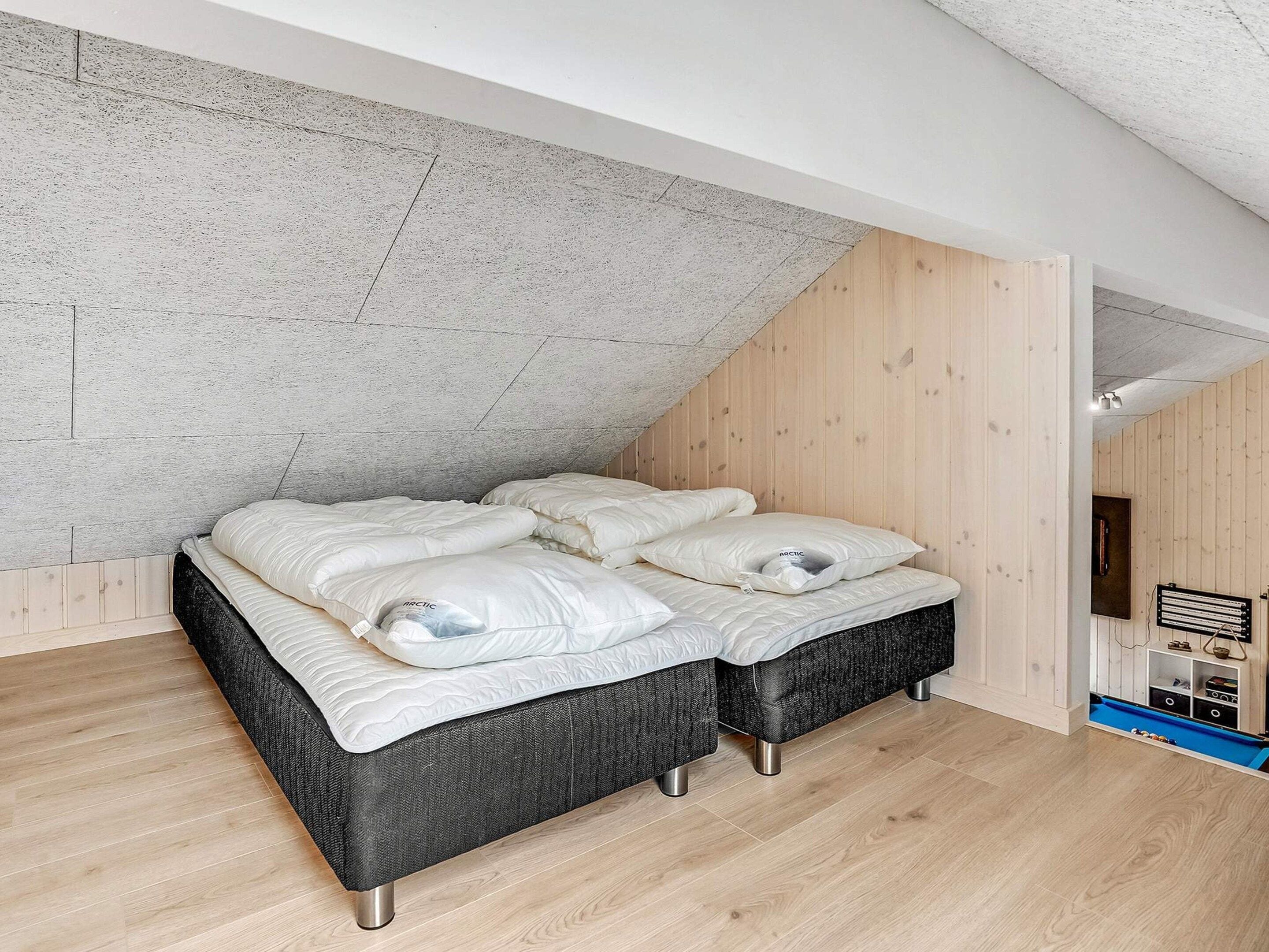 Quarto com cama beliche, paredes de madeira e teto inclinado.